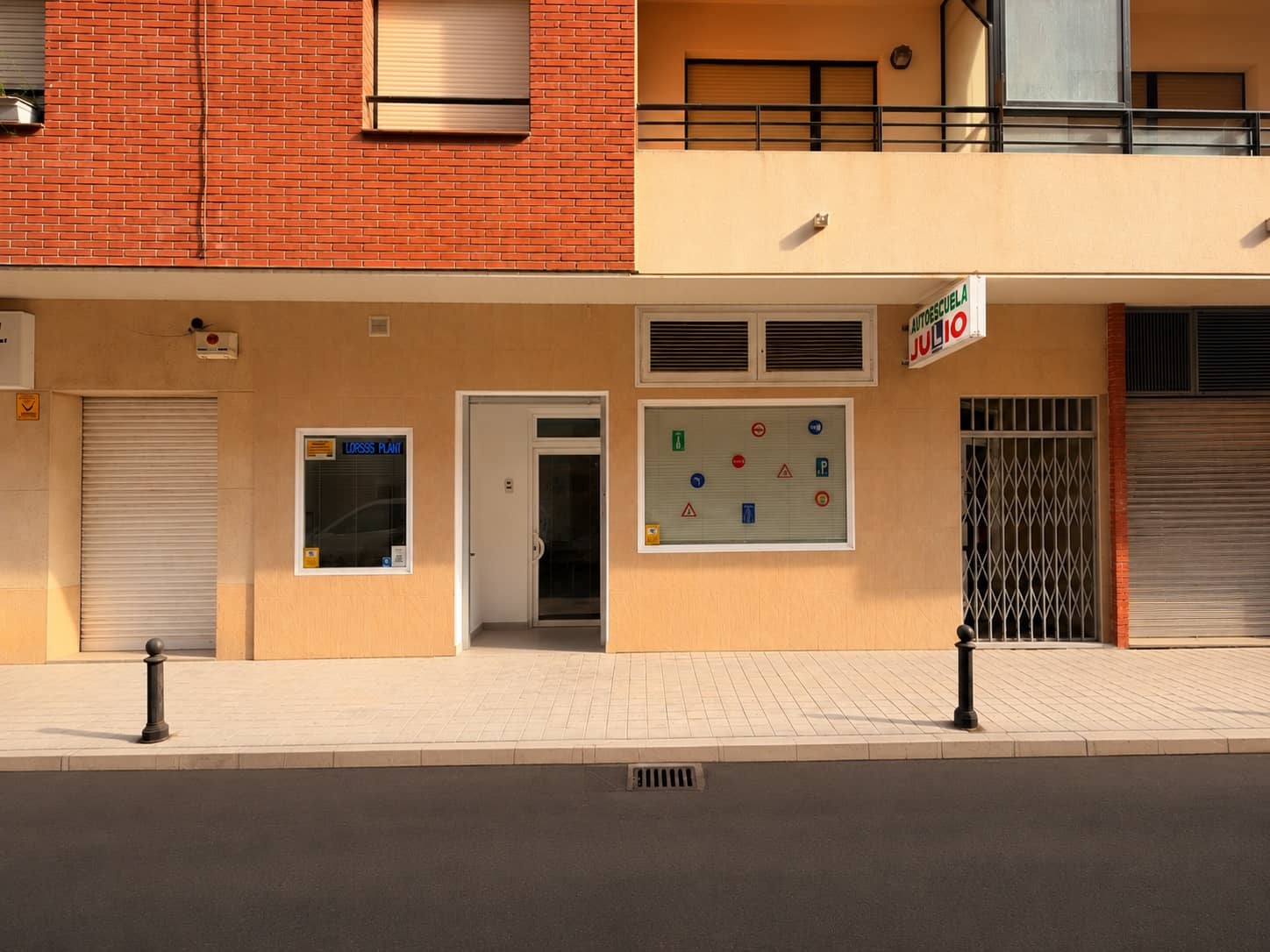Fachada de Autoescuela Julio en Ciudad Real, con señales de tráfico en el escaparate